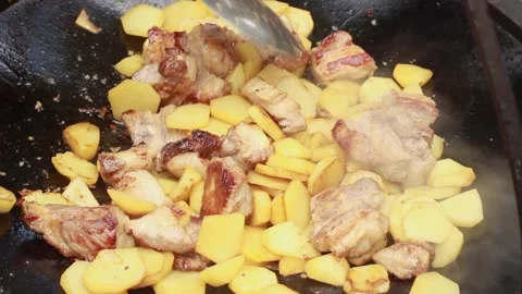 Fry potatoes with meat on a fire in a giant frying pan on a summer sunny day, cl Stock Footage 136569940