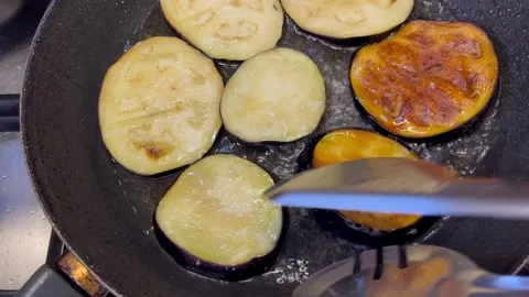 Frying and Flipping Eggplant Slices in a Pan Stock Footage 345321094