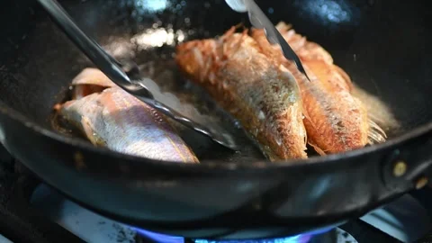 Frying and flipping the fish with a tong Stock Footage 252252500
