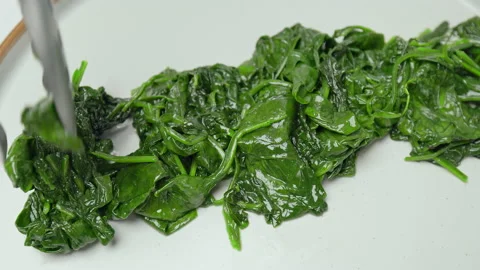 Frying and mixing spinach into a frying pan in slow-motion in 4k. Stock Footage 146000644