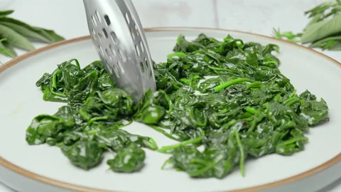 Frying and mixing spinach into a frying pan in slow-motion in 4k. Stock Footage 146001473