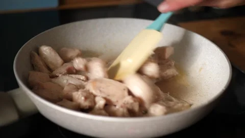 Frying and stirring with a kitchen spatula chicken meat pieces nuggets Stock-Footage 315342645