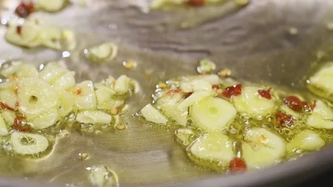Frying and stirring of sliced garlic and hot peppers in a frying pan. Stock Footage 152529563