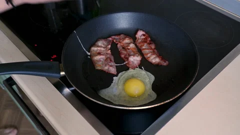 Frying bacon and eggs for breakfast. Fry the Bacon Pieces in a Pan. Stock Footage 152250988