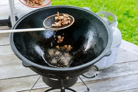 Frying bacon in cauldron on fire outside. Stock Photos