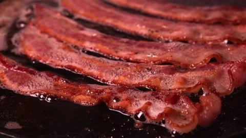 Frying bacon meat on the stove, close up view. Tasty Bacon strips being cooked. 스톡 동영상 334642620