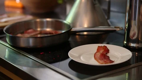 Frying bacon in a pan on a stove in modern home kitchen Video stock 97441210