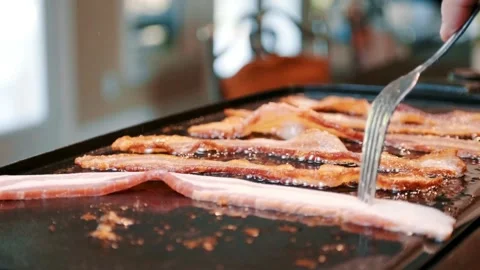 Frying bacon slices on a pan in kitchen for breakfast. Closeup of Frying Bacon. 스톡 동영상 334642347