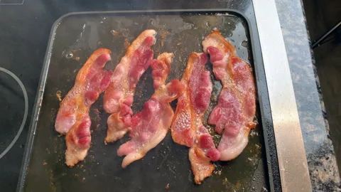 Frying bacon on a stovetop Stock Footage 166592213