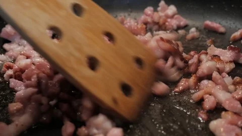Frying bacon (a type of meat) on a pan, moving the tiny pieces with a 動画素材 115859587