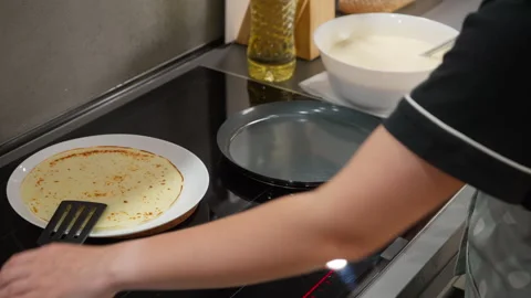 Frying a batch of thin crepes on a non-stick pan using an induction stove Stock-Footage 315358712