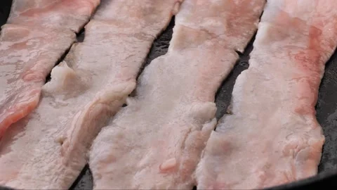 Frying beef in a cast iron pan in boiling oil, close-up. Frying bacon slices Video stock 242030533