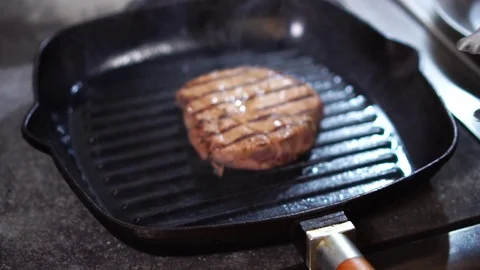 Frying beef meat steak on black grill frying pan in slow motion close up view Stock Footage 105895465