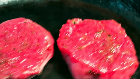 Frying beef steak on a cast-iron thick frying pan. The sparks of flame are fly Stock Footage 88443194