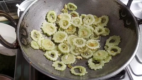 Frying bitter gourd in a small wok Stock Footage 156244043