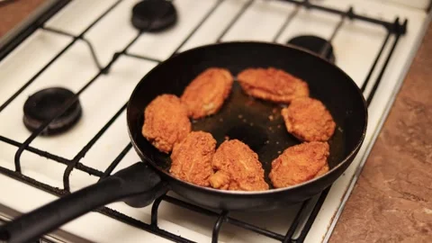 Frying breaded chicken cutlets in a pan on a gas stove for a delicious meal Stock Footage 338996634