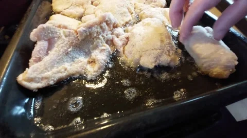 Frying breaded meat cutlets in hot sizzling oil on a pan Stock Footage 334393324