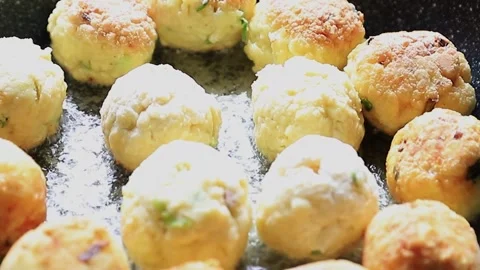 Frying breadfruit balls in shallow coconut oil Stock Footage 147439419