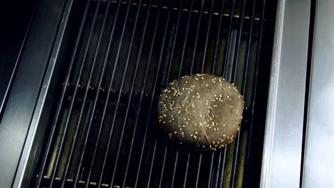 Frying buns on kitchen grill. Chef's hand putting halves of black buns Stock Footage 318310324
