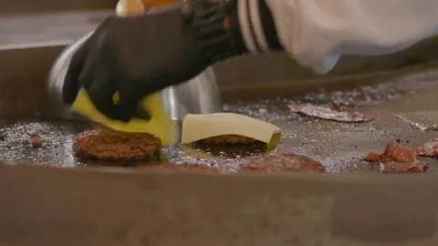Frying burger with melting cheese on them with smoke and fire. Cook's hands. 库存影片 219725933