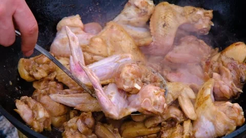 Frying chicken in a cauldron. Chicken meat in a cauldron. Outdoor cooking Stock Footage 280928908