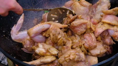 Frying chicken in a cauldron. Chicken meat in a cauldron. Outdoor cooking Stock Footage 284173811
