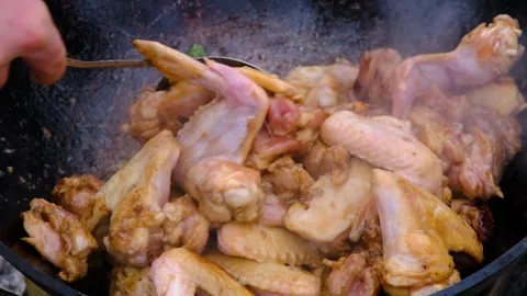 Frying chicken in a cauldron. Chicken meat in a cauldron. Outdoor cooking Stock Footage 309006768