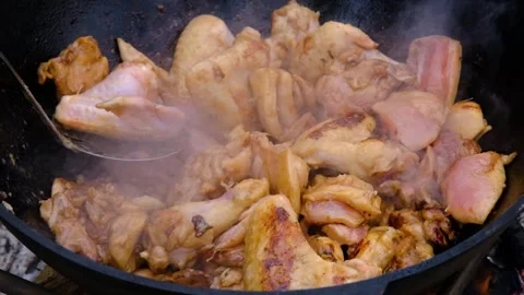 Frying chicken in a cauldron. Chicken meat in a cauldron. Outdoor cooking Stock Footage 316391516