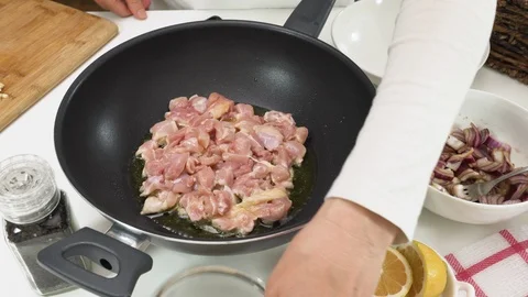 Frying chicken meat on a frying pan, add some seasoning salt and black pepper.  Stock Footage 126349129