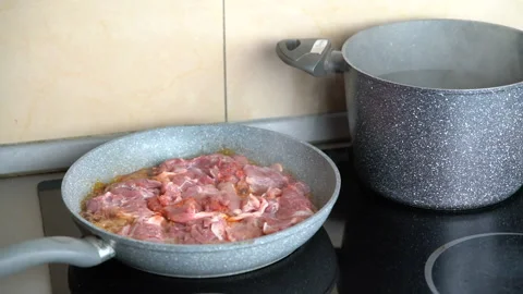 Frying chicken thighs on pan, boiling water in background Stock Footage 161158293