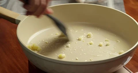 Frying chopped garlic in vegetable oil in pan close up cooking process Vídeos de archivo 333325409
