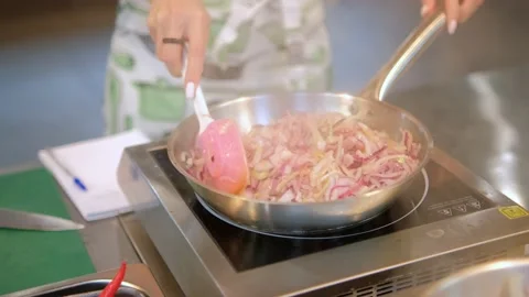 Frying chopped onion in frying pan. Slow motion. Chef pouring down pieces of Stock Footage 221837239
