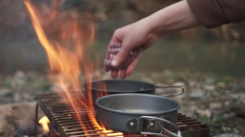 Frying chopped onion in frying pan on bonfire near river Stock Footage 271548365