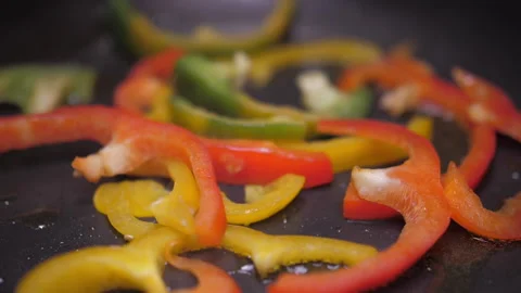 Frying chopped red, green, yellow bell pepper on fry pan  Stock Footage 149705714