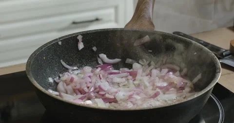 Frying chopped red onion in a frying pan. Sizzling red onions frying in oil Stock Footage 278483778