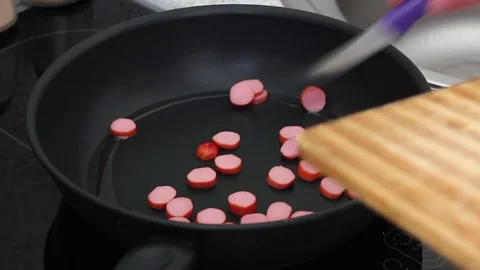 Frying chopped small sausages in a black frying pan close-up for morning Stock Footage 158184113