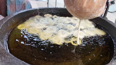 Frying crispy dough rings in street kitchen at local market Stockbeeldmateriaal 302054093
