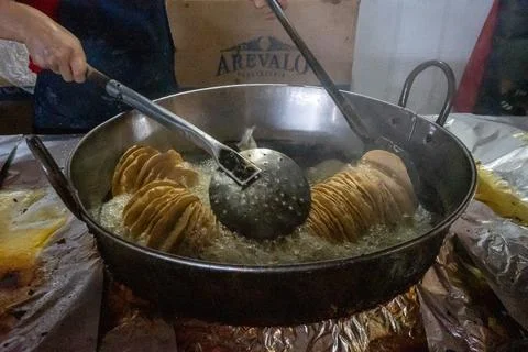 Frying crispy spiral potato chips in hot oil at a vibrant farmer's market. Stock-Fotos