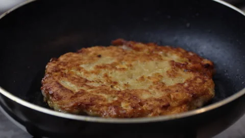 Frying a crispy yellow split pea patty in a hot frying pan on the stove Vídeo Stock 347078588