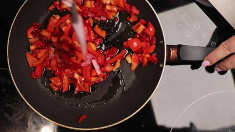 Frying diced red bell pepper in hot pan with oil, top view closeup cooking Stock Footage 317106921