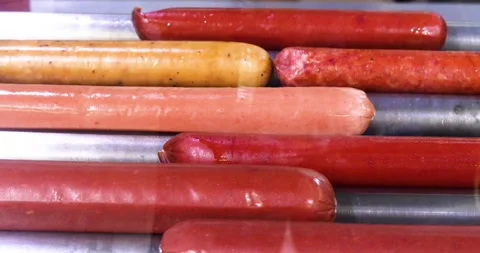 Frying different types of hotdog sausages on a roller grill Stock Footage 333040978