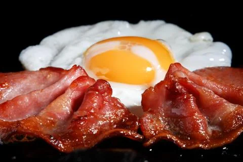 Frying egg and two bacon rashers Stock Photos
