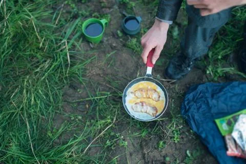 Frying egg with bacon in pan on camp gas. Top view. Stock Photos