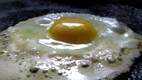 Frying egg in black pan closeup Stock Footage 136158696