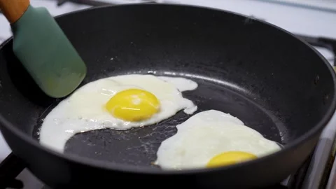 Frying Egg in a Cooking Pan, close-up. Man hands using silicone spatula Video stock 272156201