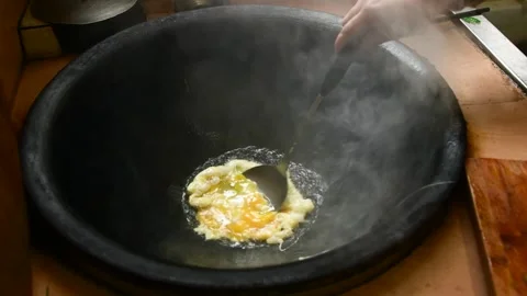 Frying Egg in Large Black Iron Wok with Steam Stock Footage 340934745