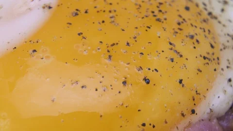 Frying eggs and bacon with black pepper, macro shot Stock Footage 127418441
