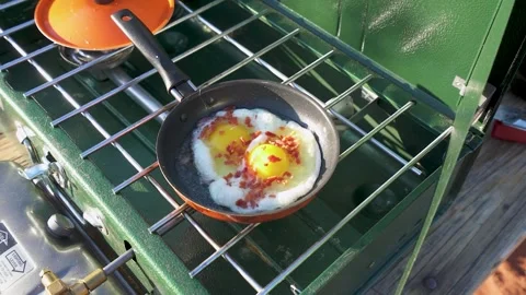 Frying eggs on a camping stove. 库存影片 282389782