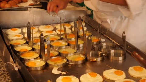 Frying eggs in round metal molds in the kitchen of a hotel restaurant Stock Footage 294322210