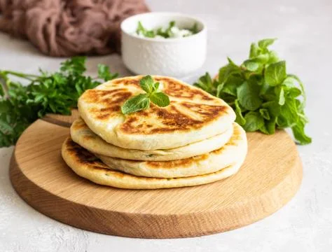 Frying flatbread filled with herbs and cheese. Stock Photos
